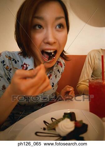 Stock Photography - Young woman eating dessert. Fotosearch