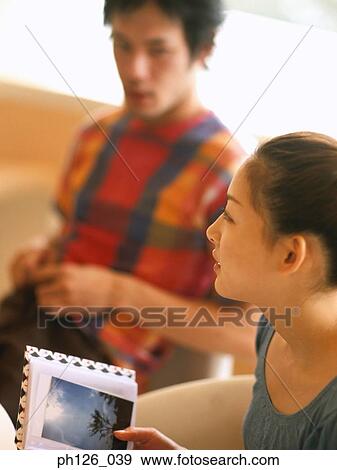 Young woman holding photo album, man in the background View Large Photo Image Stock Photo - Young woman holding photo album, man in the background. Fotosearch