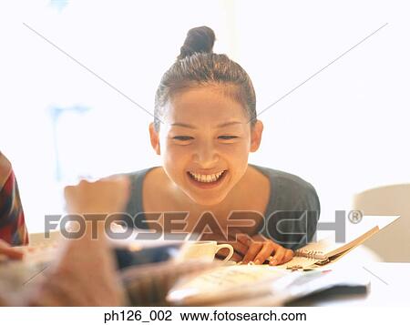Stock Image - Young woman looking at menu, laughing. Fotosearch