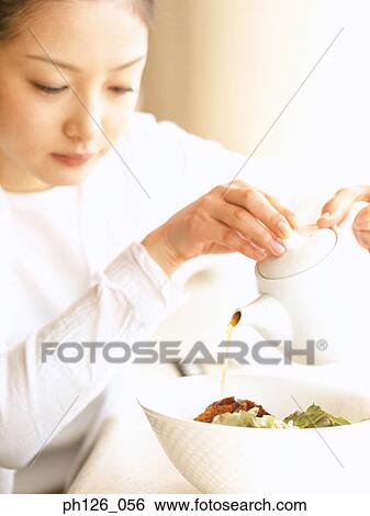 Young woman pouring sauce into a bowl of salad View Large Photo Image Stock Photograph - Young woman pouring sauce into a bowl of salad. Fotosearch