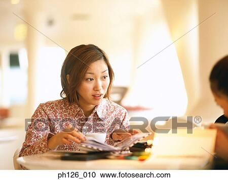 Young woman talking to her friend at a café View Large Photo Image Stock Image - Young woman talking to her friend at a café. Fotosearch