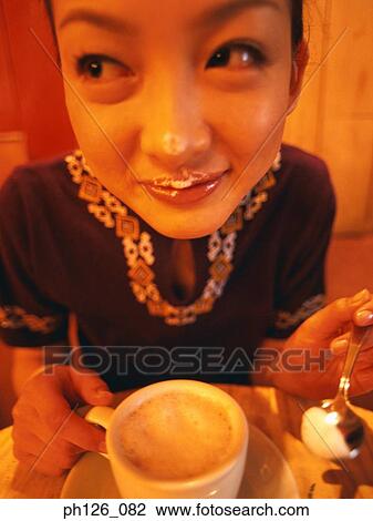 Stock Image - Young woman with coffee form on her lips. Fotosearch