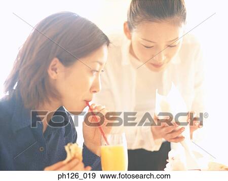 Stock Photo - Young women at a café, eating snacks. Fotosearch