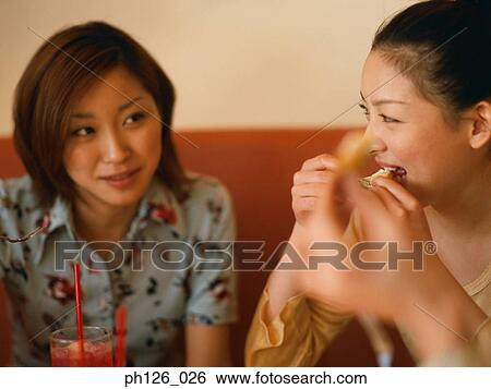 Young women at a café, eating snacks View Large Photo Image Stock Photograph - Young women at a café, eating snacks. Fotosearch