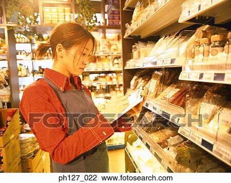 Stock Image - Female store attendant doing stock-take. Fotosearch