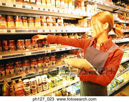 Stock Image - Female store attendant doing stock-take. Fotosearch