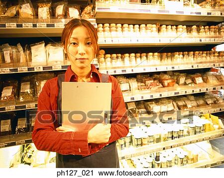 Stock Image - Female store attendant in grocery store. Fotosearch