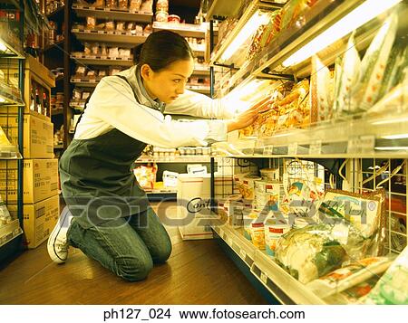 Picture - Female store attendant packing grocery. Fotosearch