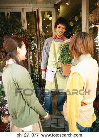 Stock Photo - Male florist talking to female customers. Fotosearch