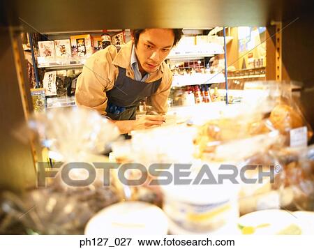 Stock Photo - Male store attendant checking grocery. Fotosearch