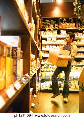 Male store attendant replenishing grocery View Large Photo Image Picture - Male store attendant replenishing grocery . Fotosearch