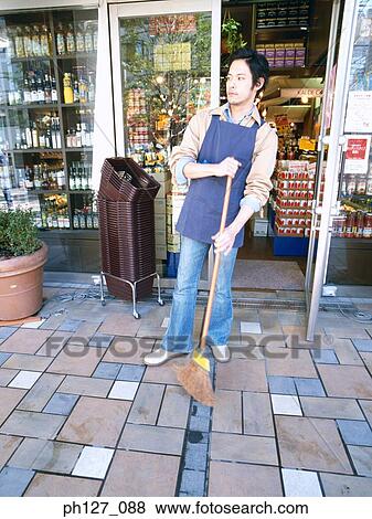 Male store attendant sweeping outside a grocery store View Large Photo Image Stock Photo - Male store attendant sweeping outside a grocery store. Fotosearch