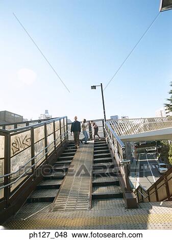 Stock Photo - Three friends walking and playing at overhead bridge. Fotosearch