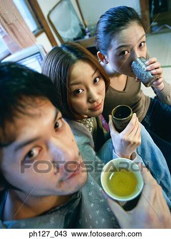 Stock Image - Three young adults drinking green tea. Fotosearch