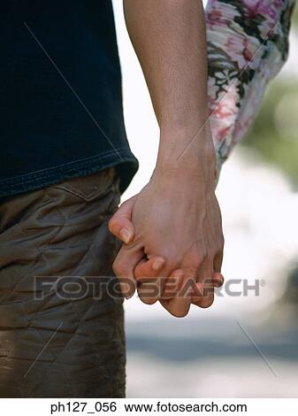 Stock Photograph - Young couple holding hands, close-up. Fotosearch