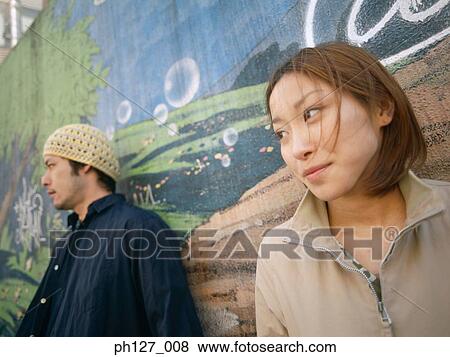 Stock Photo - Young couple standing against painted wall. Fotosearch