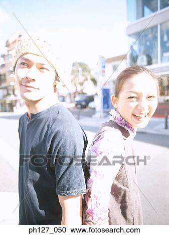 Young couple standing back to back, smiling View Large Photo Image Stock Image - Young couple standing back to back, smiling. Fotosearch