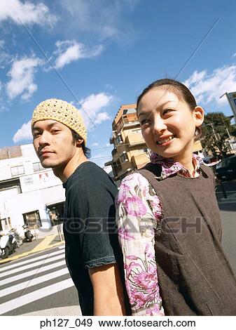 Young couple standing back to back, smiling View Large Photo Image Stock Photo - Young couple standing back to back, smiling. Fotosearch