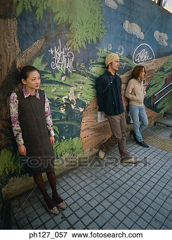Young friends standing against painted wall View Large Photo Image Stock Photo - Young friends standing against painted wall. Fotosearch