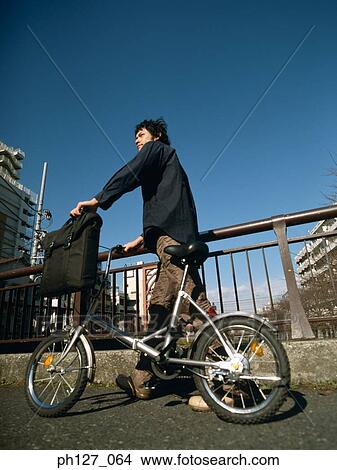 Young man holding a bicycle View Large Photo Image Picture - Young man holding a bicycle. Fotosearch