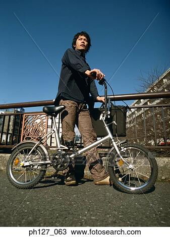 Young man holding a bicycle View Large Photo Image Stock Image - Young man holding a bicycle. Fotosearch
