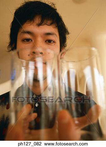 Young man holding two glasses, close-up View Large Photo Image Stock Image - Young man holding two glasses, close-up. Fotosearch