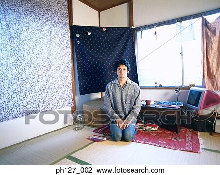 Stock Image - Young man kneeling (sitting). Fotosearch