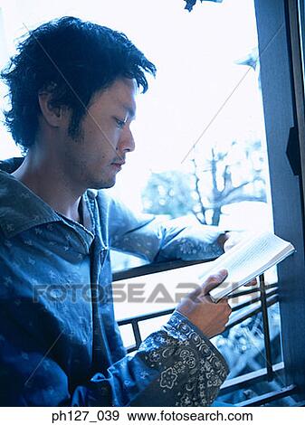 Young man reading by the window View Large Photo Image Stock Photo - Young man reading by the window. Fotosearch