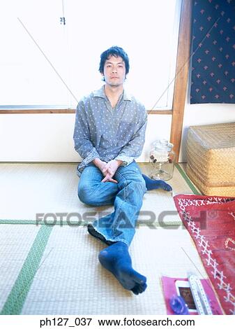 Young man sitting in his room View Large Photo Image Stock Photo - Young man sitting in his room. Fotosearch