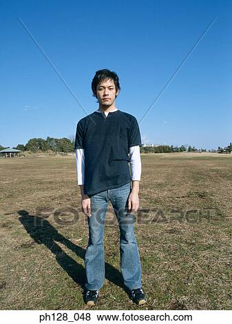 Portrait of a young man standing at a field View Large Photo Image Stock Photo - Portrait of a young man standing at a field. Fotosearch