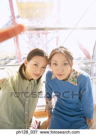 Stock Photo - Portrait of two young women, looking at camera. Fotosearch