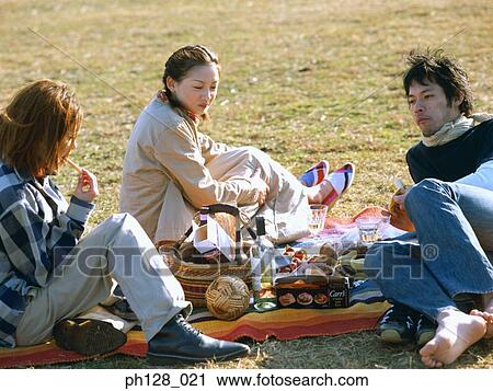 Stock Image - Three friends having picnic. Fotosearch