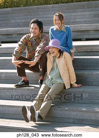 Three friends sitting on steps, smiling View Large Photo Image Stock Image - Three friends sitting on steps, smiling. Fotosearch