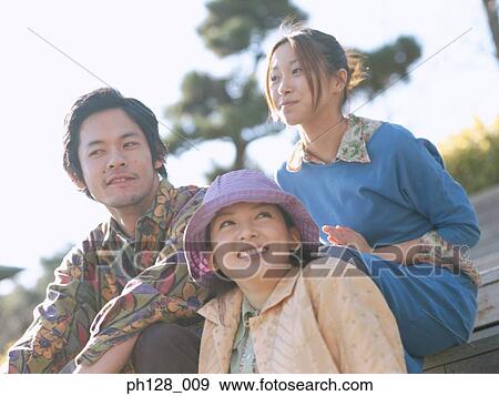 Stock Photo - Three friends sitting on steps, smiling. Fotosearch