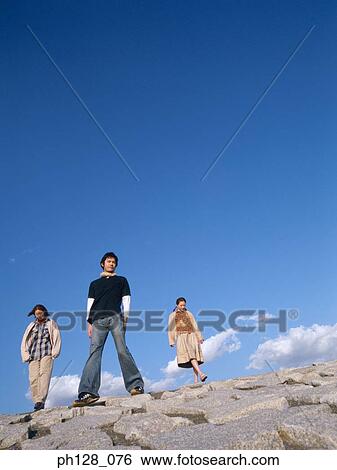Three people standing on water-breaker View Large Photo Image Stock Photograph - Three people standing on water-breaker. Fotosearch