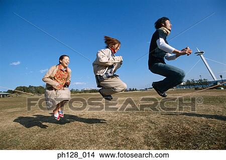 Picture - Three young people hopping and laughing. Fotosearch