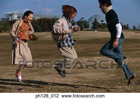 Stock Image - Three young people hopping and laughing. Fotosearch
