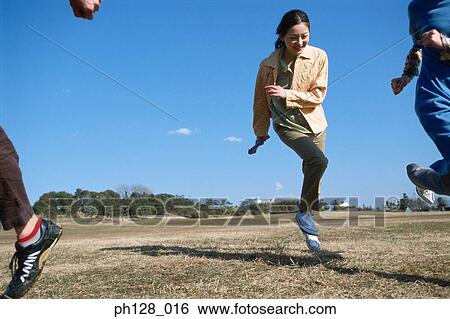 Stock Photograph - Three young people hopping and laughing. Fotosearch