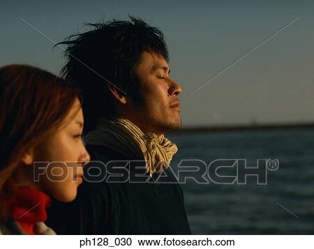 Stock Image - Young couple at the beach, side profile. Fotosearch
