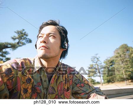 Young man listening to headphones, looking away View Large Photo Image Stock Image - Young man listening to headphones, looking away. Fotosearch