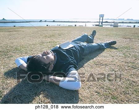 Stock Photo - Young man lying on the field. Fotosearch