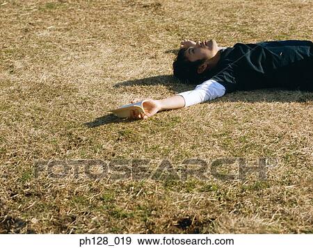 Young man lying on the field View Large Photo Image Stock Photo - Young man lying on the field. Fotosearch