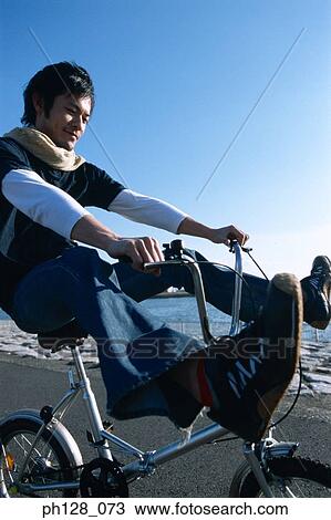 Young man riding on bicycle, with his legs raised View Large Photo Image Stock Image - Young man riding on bicycle, with his legs raised. Fotosearch