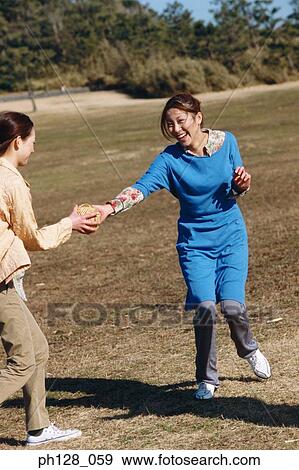 Stock Photo - Young woman passing a ball to her friend. Fotosearch