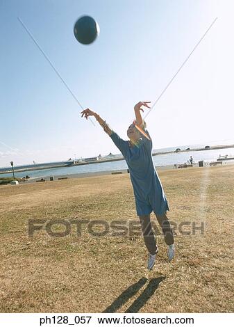 Stock Photo - Young woman throwing a ball . Fotosearch