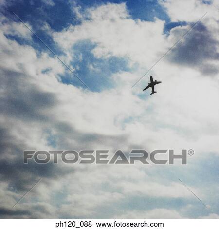 Stock Photo - Airplane flying across blue sky, silhouette. Fotosearch