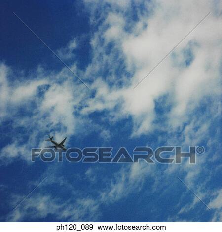 Stock Photo - Airplane flying across blue sky, silhouette. Fotosearch