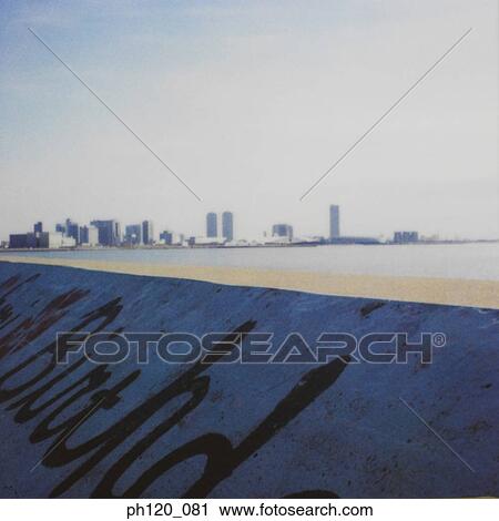 Stock Image - Concrete slope with wordings painted, city in the background. Fotosearch