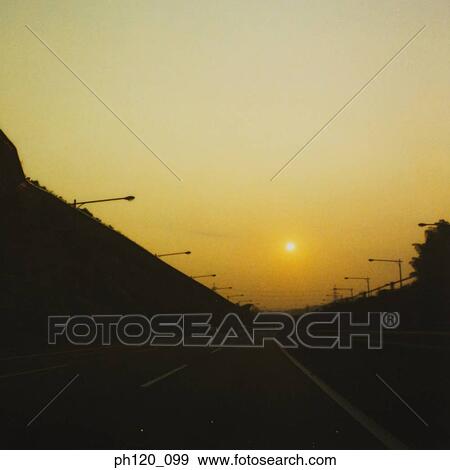 Stock Photo - Empty road and street lamps at sunset. Fotosearch