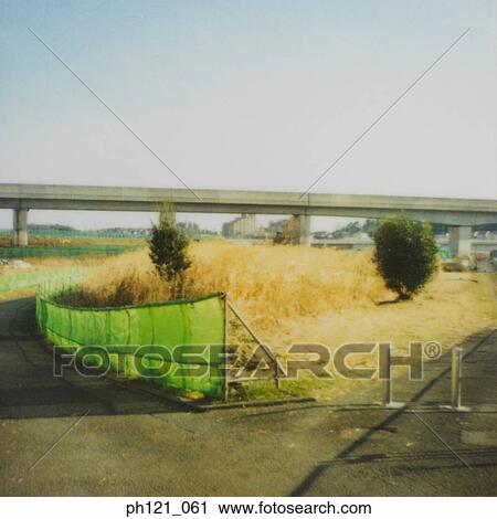 Stock Image - Deserted field, partially fenced. Fotosearch